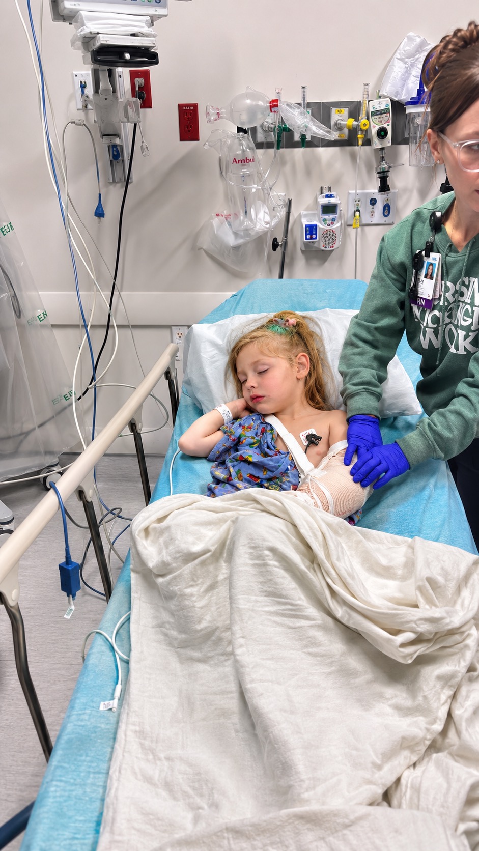 Willow lying in an emergency room bed while a nurse tends to her splinted arm